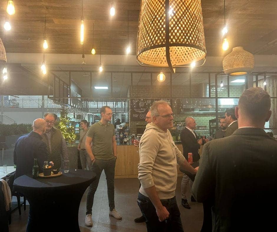 Trevor Terry meeting with Dutch partners in an informal drinks and networking setting. People stand around tables in discussion.